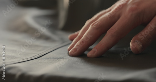 Bild auf Leinwand closeup man hand checking seam on soft gray leather clothes