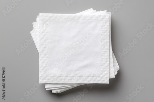 Top-down view of a neatly stacked pile of white, square paper napkins on gray background