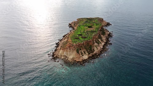Aerial drone view of a small island off the coast of Cyprus. Natural Mediterranean seascape showing isolated landform surrounded by open sea.