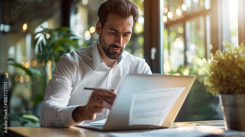 Businessman managing digital document workflow on laptop in modern corporate office environment
