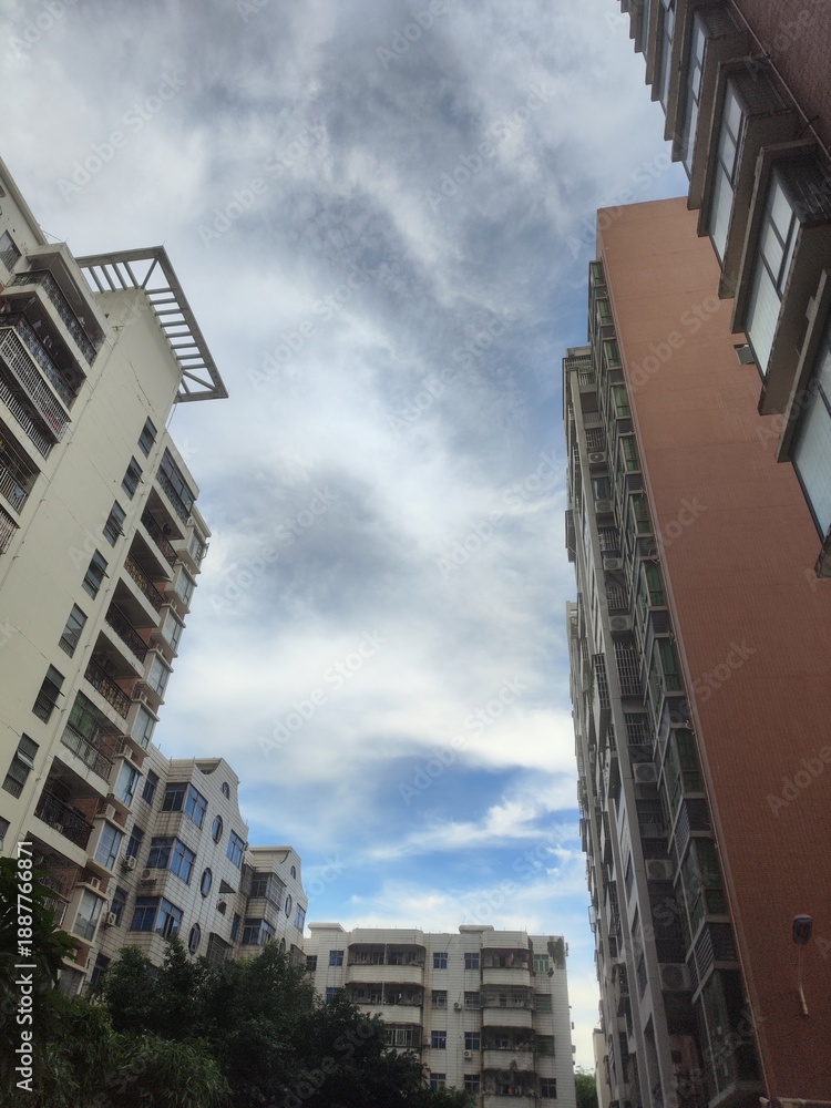 Fototapeta premium Tall apartment buildings under a cloudy sky, urban residential scene