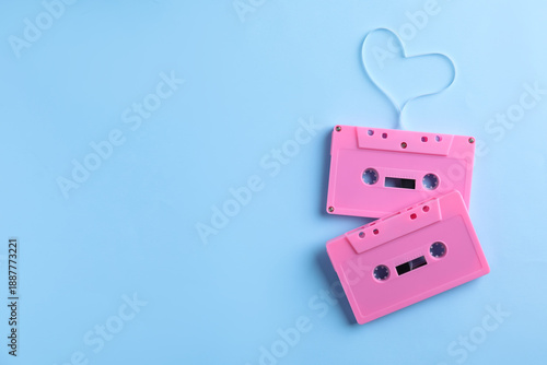 Music cassettes and heart made with tape on light blue background, top view. Space for text