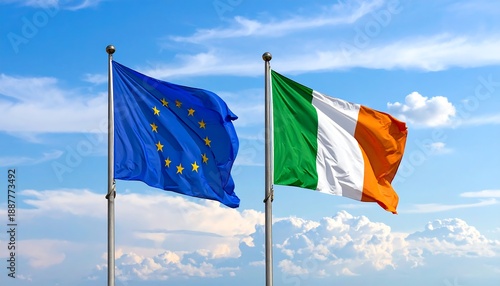 Two flags, one with stars and one with stripes, fly against a bright blue cloudy sky