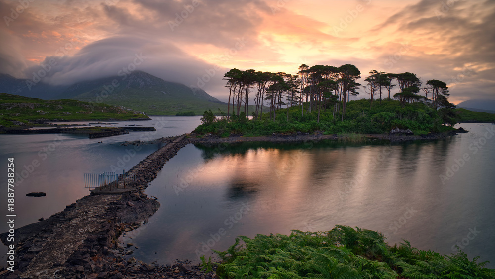 Fototapeta premium Dramatic Sunrise over Twelve Pines Island on Derryclare Lough in Connemara, County Galway, Ireland, Featuring Misty Mountains and Reflective Water, travel scenic landscape background