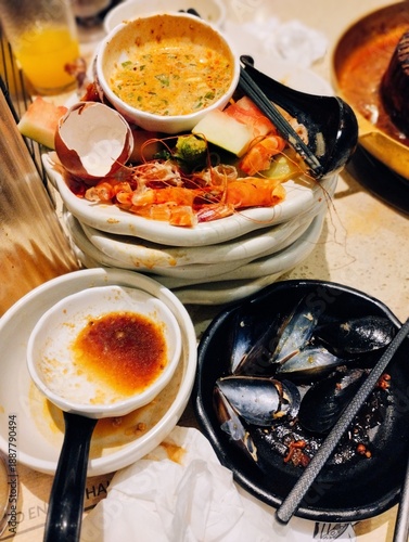 Εκτύπωση καμβά Stacked dirty plates and bowls with leftover seafood shells, mussels, and sauce after a restaurant meal, depicting food waste and the end of a dining experience