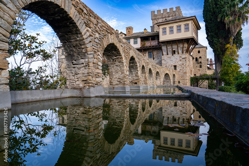 Canvastavla Stone courtyard with an arched aqueduct, reflection pool, and medieval tower in Hilander Monastery on Mount Athos