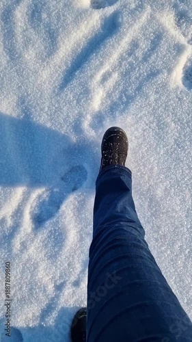 First person view of feet walking in the snow. Winter walk. Female feet in jeans and winter shoes walking in the snow. Kicking snow with feet while walking. Active lifestyle