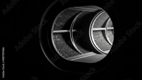 Close-up of a metal air vent or filter against a dark background.