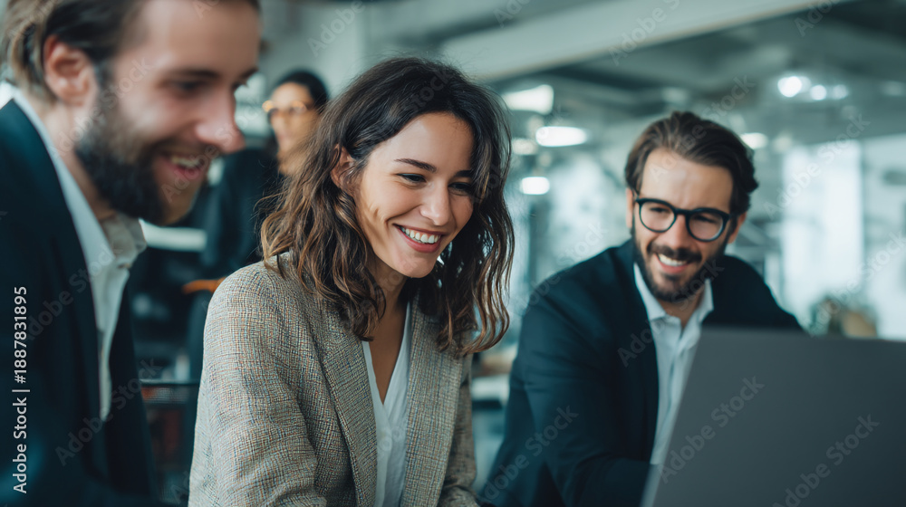 Obraz premium A group of smiling business colleagues gathered around a laptop in a modern office setting