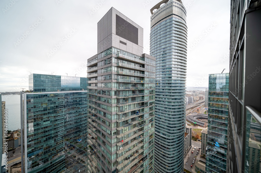 Fototapeta premium Urban toronto skyline featuring contemporary residential and commercial skyscrapers with glass facades, reflecting the cloudy sky over the city and waterfront. In mimco