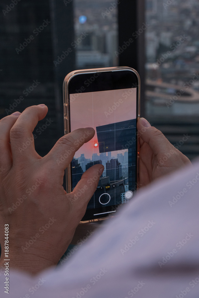 Obraz premium Person photographing or taking video of city skyline at sunset with smartphone