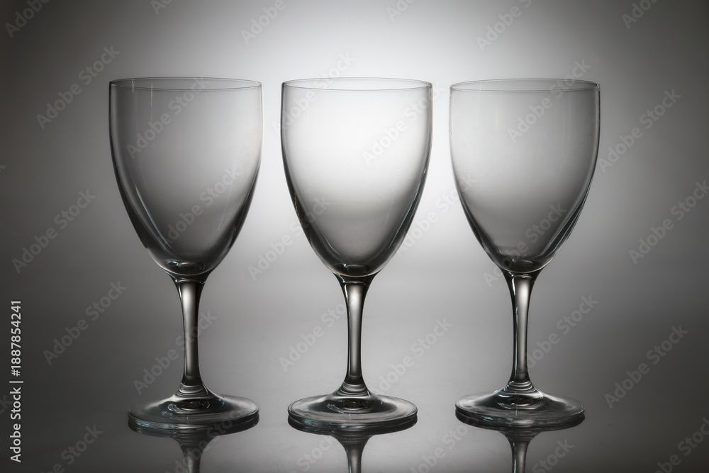 Fototapeta premium Three empty wine glasses isolated on light background. Minimalist glassware set for restaurant, bar, wine tasting, celebration, menu design