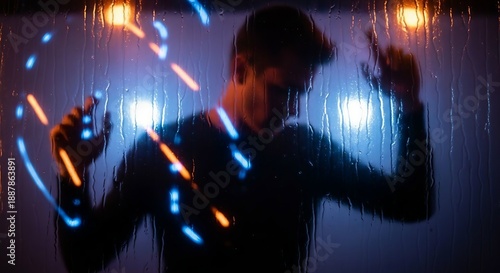 A person in silhouette behind a rainy window with glowing blue and orange light streaks, creating a dynamic and futuristic effect.