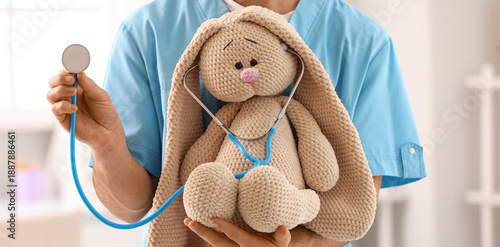 Tableau sur toile Male pediatrician with toy bunny and stethoscope in clinic, closeup