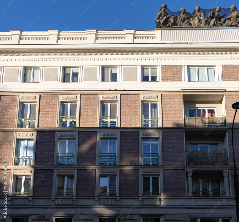Obraz premium Building with sculptures on the roof, against clear sky and afternoon light