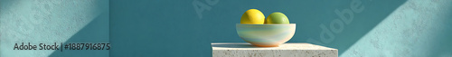 A minimalist still life composition featuring vibrant yellow and lime spheres in a pearlescent bowl, dramatically illuminate