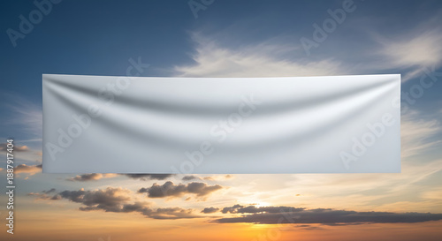 A white banner waving gently against a vibrant sunset sky with clouds, capturing a serene atmosphere and natural beauty.