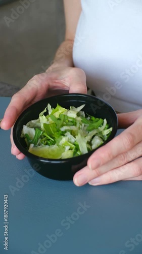 Woman hands opening black plastic container with fresh green salad, representing healthy takeaway meal concept for quick, convenient lunch break. Woman open healthy takeaway salad container for lunch