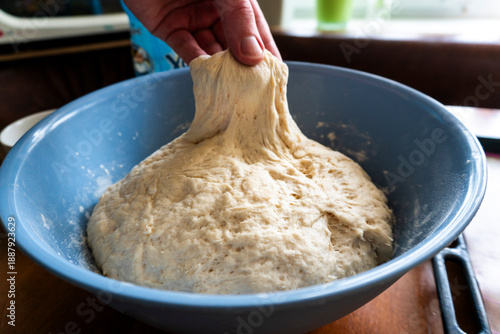 Raw yeast dough rising in a blue ceramic bowl