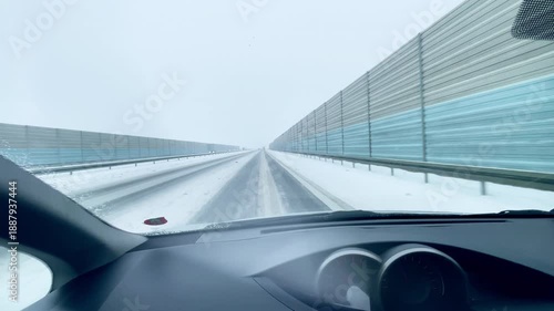 Driving a car during a snowstorm on the highway. Snow is visible on the road.