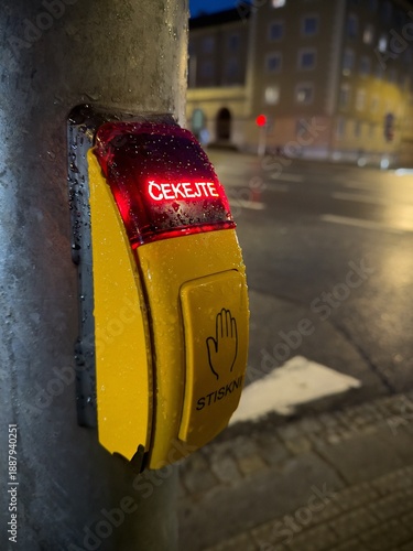 Yellow controller with Czech text STISKNI (means PRESS in translation to English) on pole near crosswalk