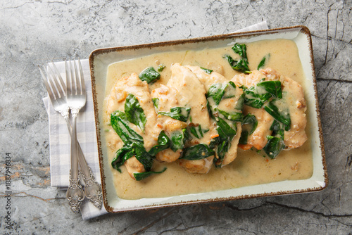 Fotografie Сhicken florentine combines a cream and white wine sauce with perfectly browned chicken breasts and fresh baby spinach close-up on a plate at the table