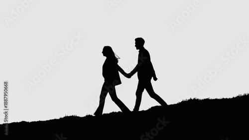 Silhouette of a romantic couple holding hands walking on a hill at sunset or dawn