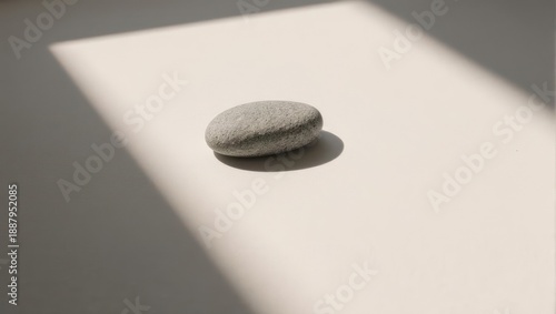 Gray smooth stone on white surface, sunbeams