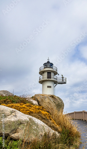 White lighthouse on rocky cliff under cloudy sky