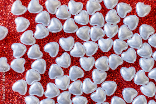 White pearl hearts on a red glittery background