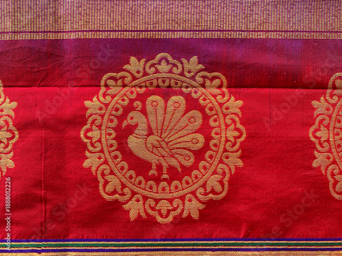 Fotografie A close-up of a traditional Indian silk saree fabric showcasing a prominent circular peacock motif intricately woven in rich golden zari