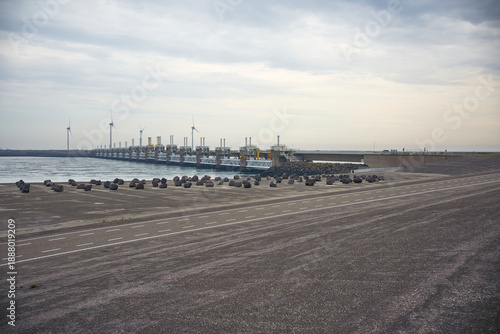 Stunning dam, deltawerke, (neeltje jans) with wind turbines and large rocks along the road, protecting the coast and generating renewable energy. Zeeland, Netherlands.