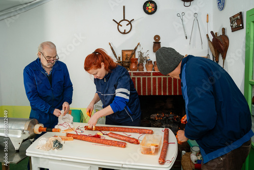 Tying chorizo ​​by hand as a family by the warmth of the fire during a traditional pig slaughter in Spain.