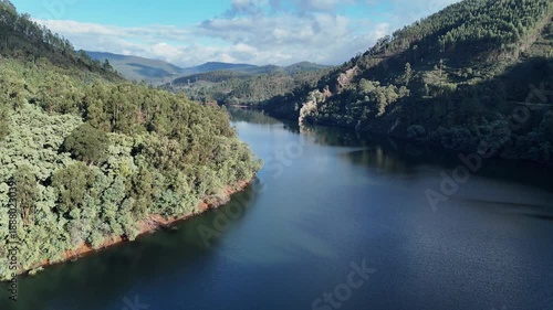 Aerial view of winding river valley in lush mountainous landscape.