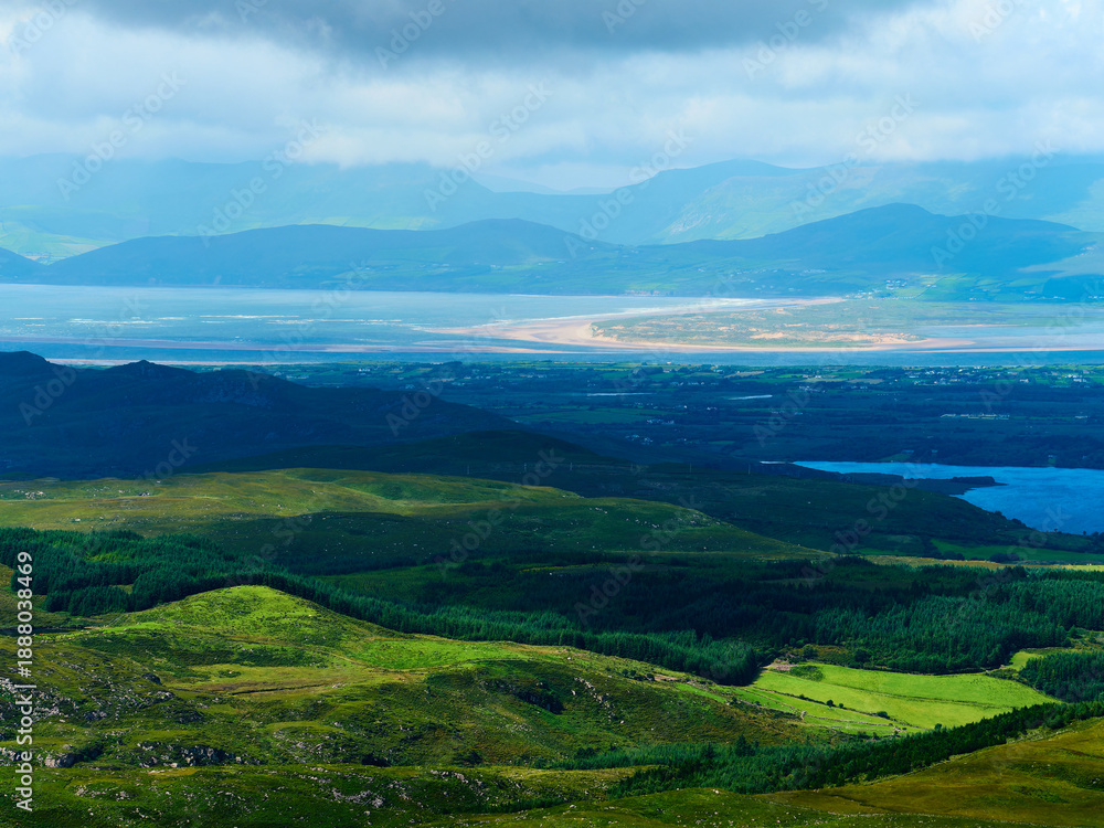 Naklejka premium Green hills and forests meet a blue lake.