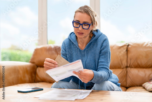 Foto Woman sitting on couch reviewing documents in a bright room with windows during