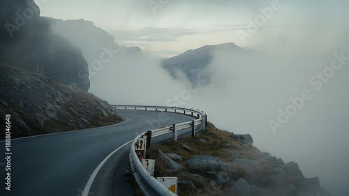 A winding coastal road disappears into thick fog and mountainous terrain