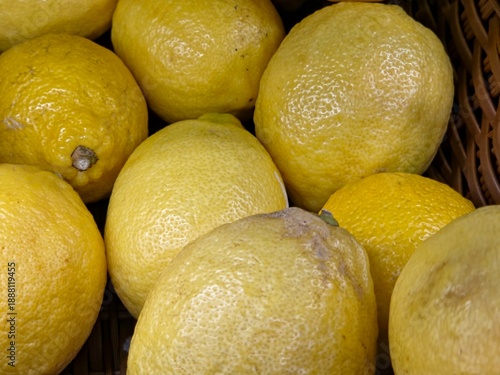 Fotografia A top-down, close-up shot of several fresh, bright yellow lemons piled together