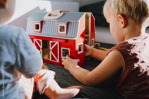 Tableau sur toile Two toddlers sitting on floor and playing with wooden farm toys
