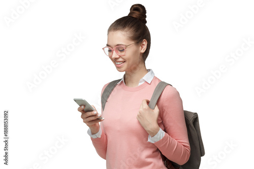 Happy young female student using smartphone with backpack, looking down