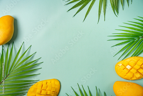 Summer colorfull concept with tropical fruits and leaves on green background, flat lay, top view, copy space