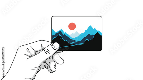 Hand holding a small photograph or postcard showing a beautiful blue mountain landscape with a red rising sun.