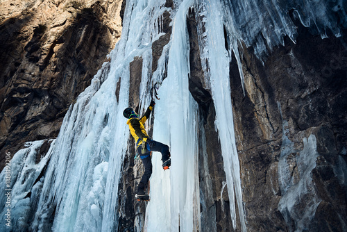 Man climbing frozen ice wall at winter mountains