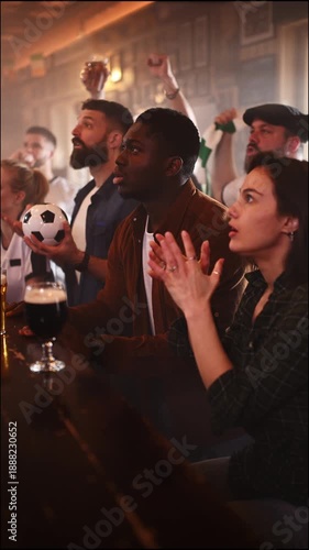 Multiethnic friends cheering for their team in a crowded sports bar