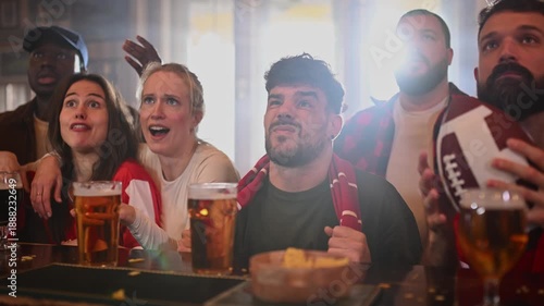 Disappointed sports fans watching a football game in a bar