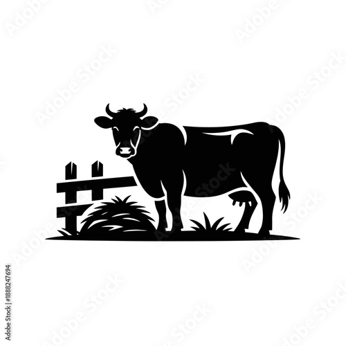 A black silhouette of a cow stands next to a fence