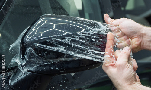 The process of installing PPF on the side mirror. PPF is a protective film for paint that protects the paint from scratches, gravel. Anti-gravity protection. Car wrapping specialists cover the car.  
