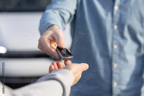Handing over car keys during vehicle purchase transaction in outdoor setting
