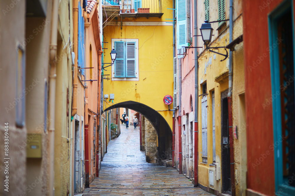 Fototapeta premium Vibrant view of colorful buildings with blue shutters and national flags in a coastal Mediterranean town