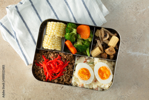 A top down view of a bento box, featuring ground beef and hard boiled eggs.